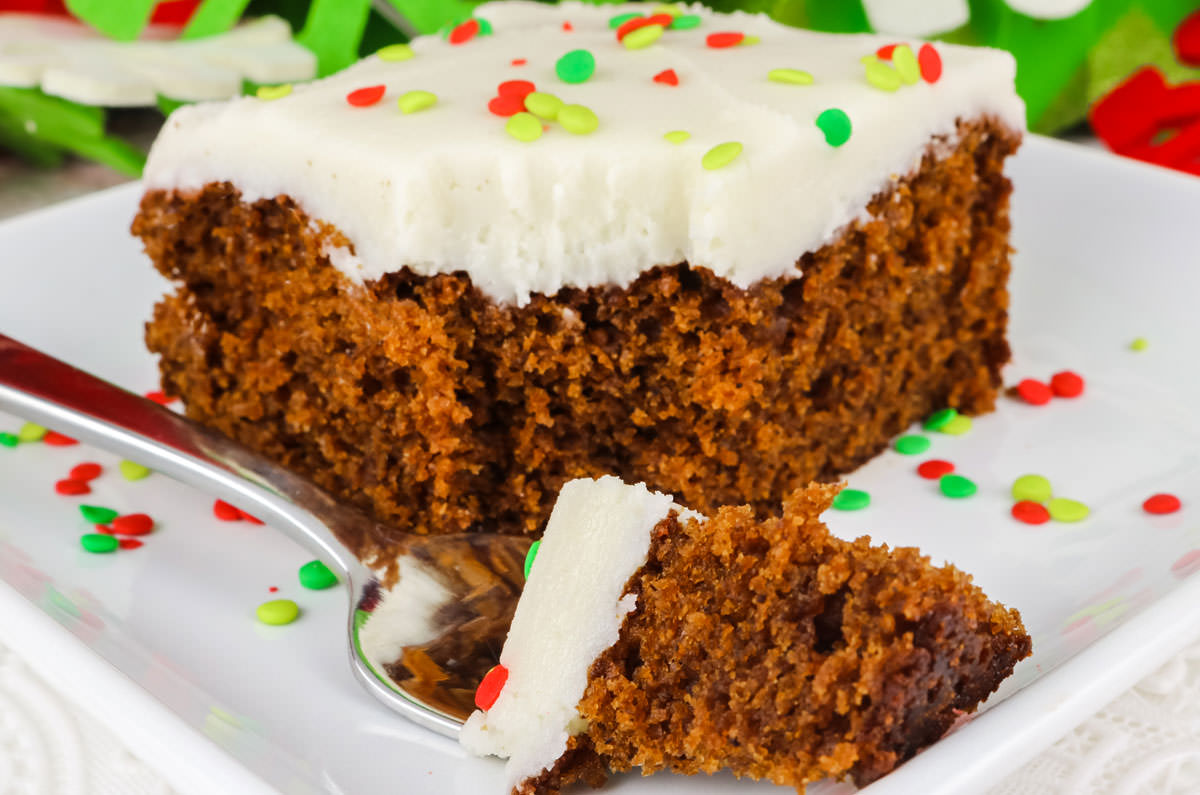 A single piece of Homemade Gingerbread Cake on a white dessert plate surrounded by Christmas Sprinkles.