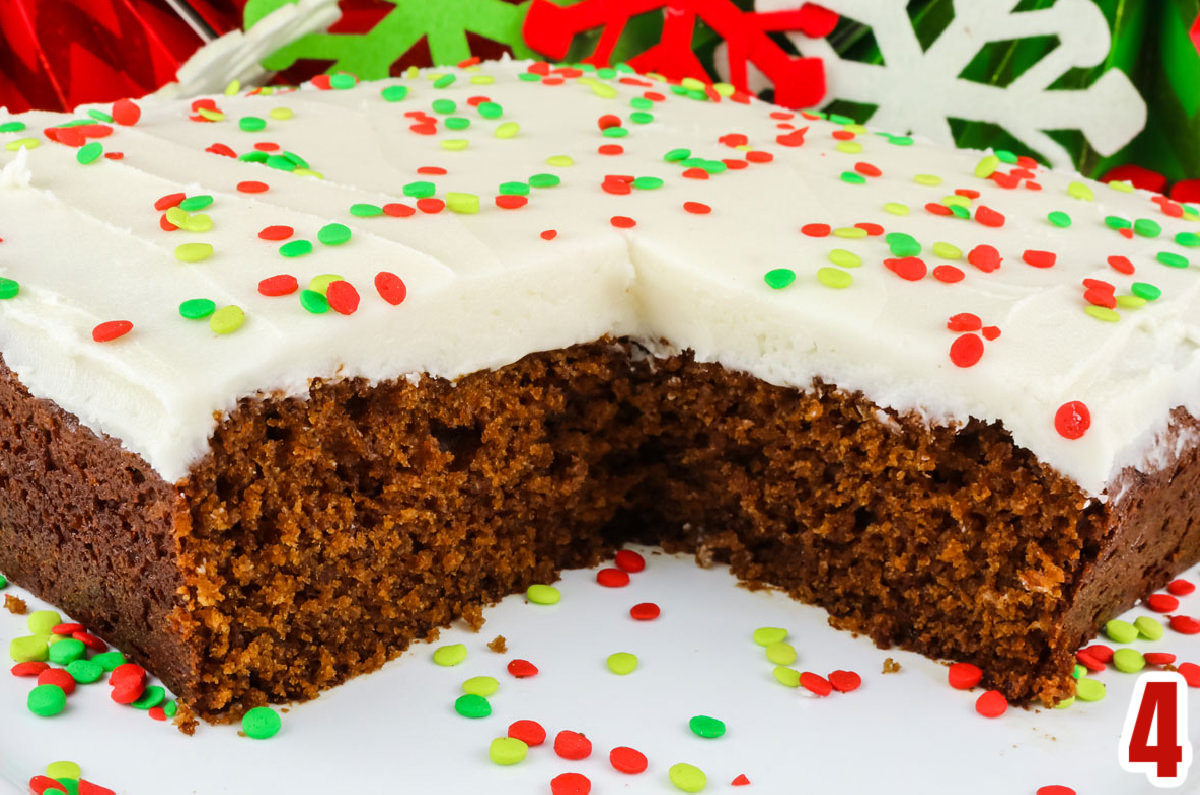 Closeup on a Homemade Gingerbread Cake on a white cake plate with one piece taken out.