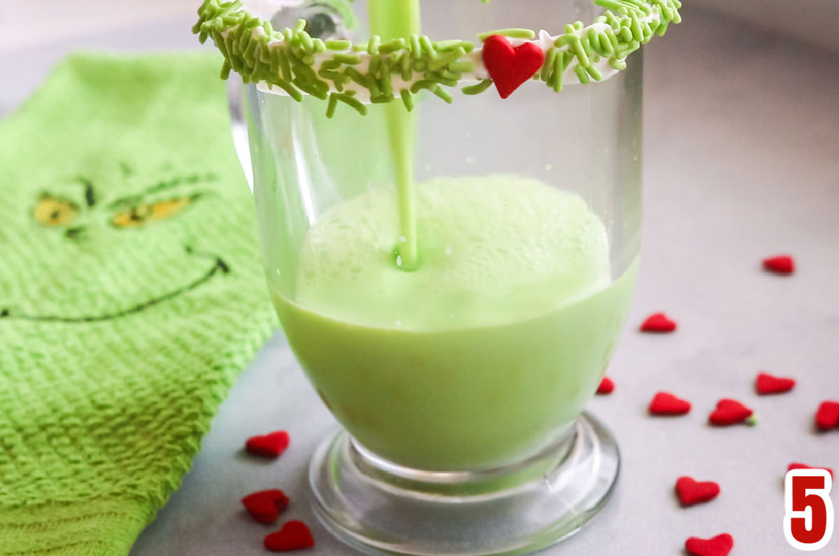 Closeup on a glass coffee mug being filled with Grinch Hot Vanilla Milk.
