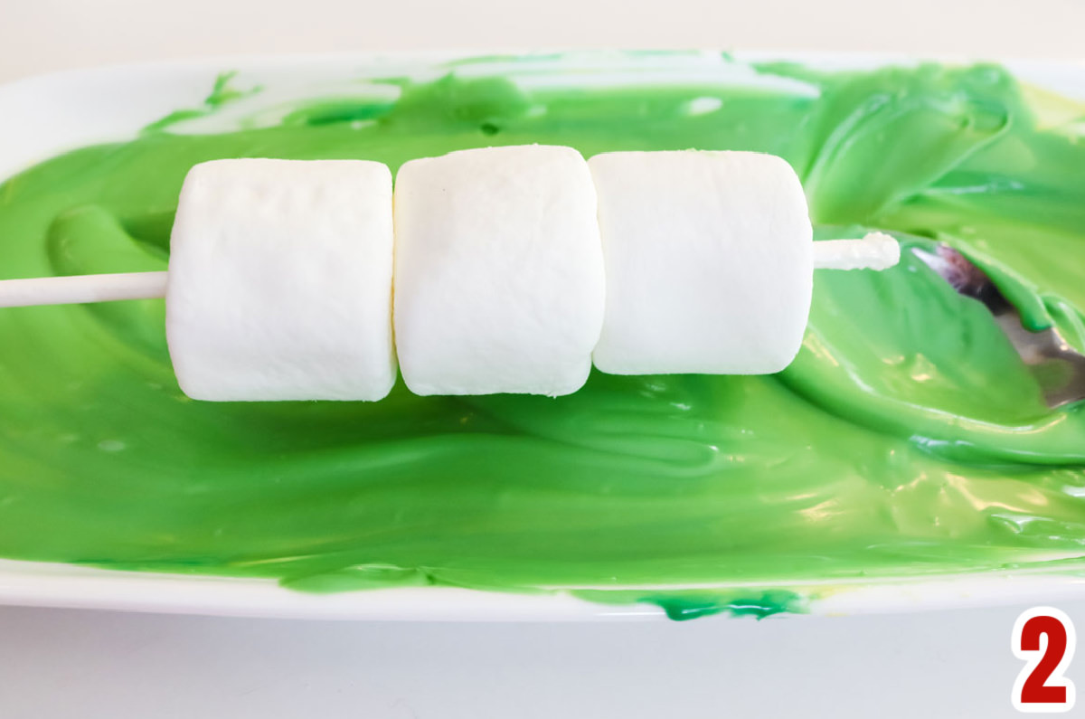 Closeup showing how to cover the Marshmallow Pop with green candy melts.