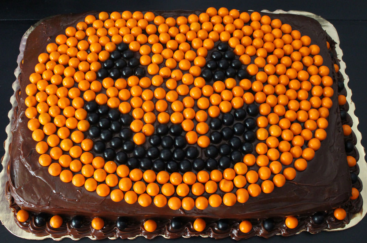 Closeup of an Easy Halloween Cake featuring a Jack o' Lantern made with orange and black Sixlets.