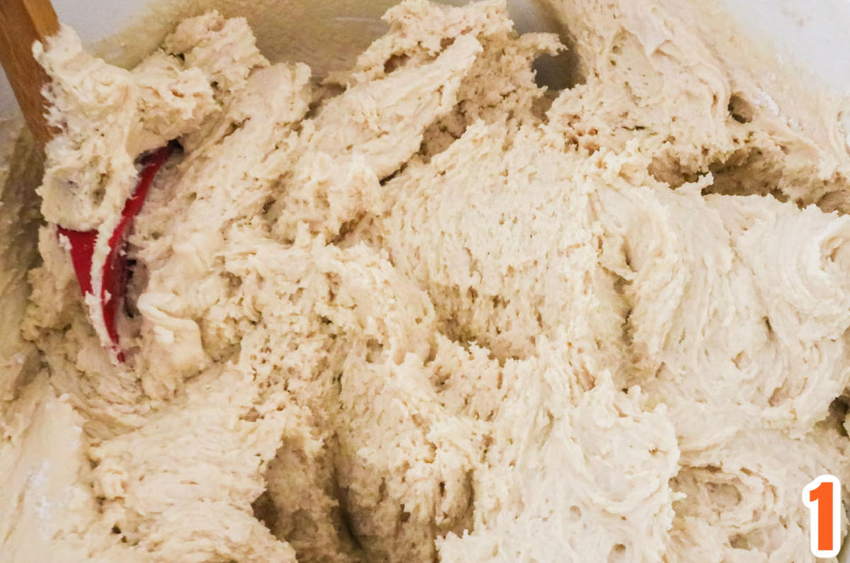 Closeup on a white mixing bowl filled with Chocolate Chip Cookie dough and a red snow.