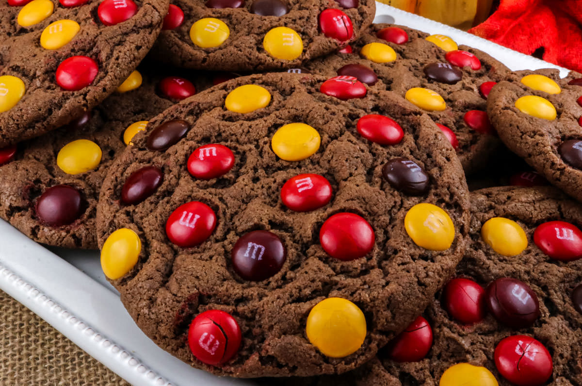 Closeup on a white serving platter filled with a batch of Harvest M&M Cookies.
