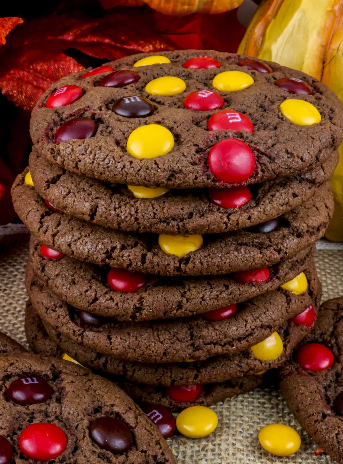 Closeup on a stack of Harvest M&M Cookies sitting in front of Fall decorations.