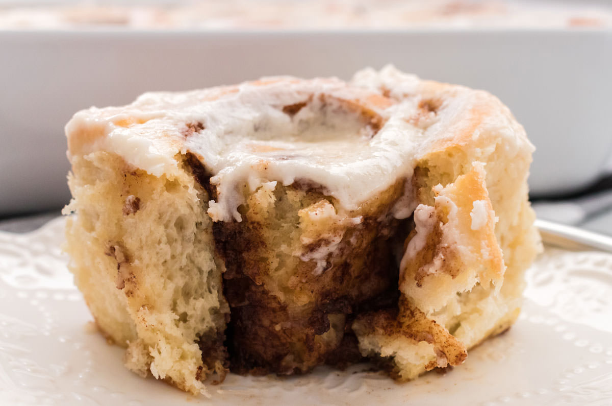 Frosted Homemade Cinnamon Roll sitting on a white plate.