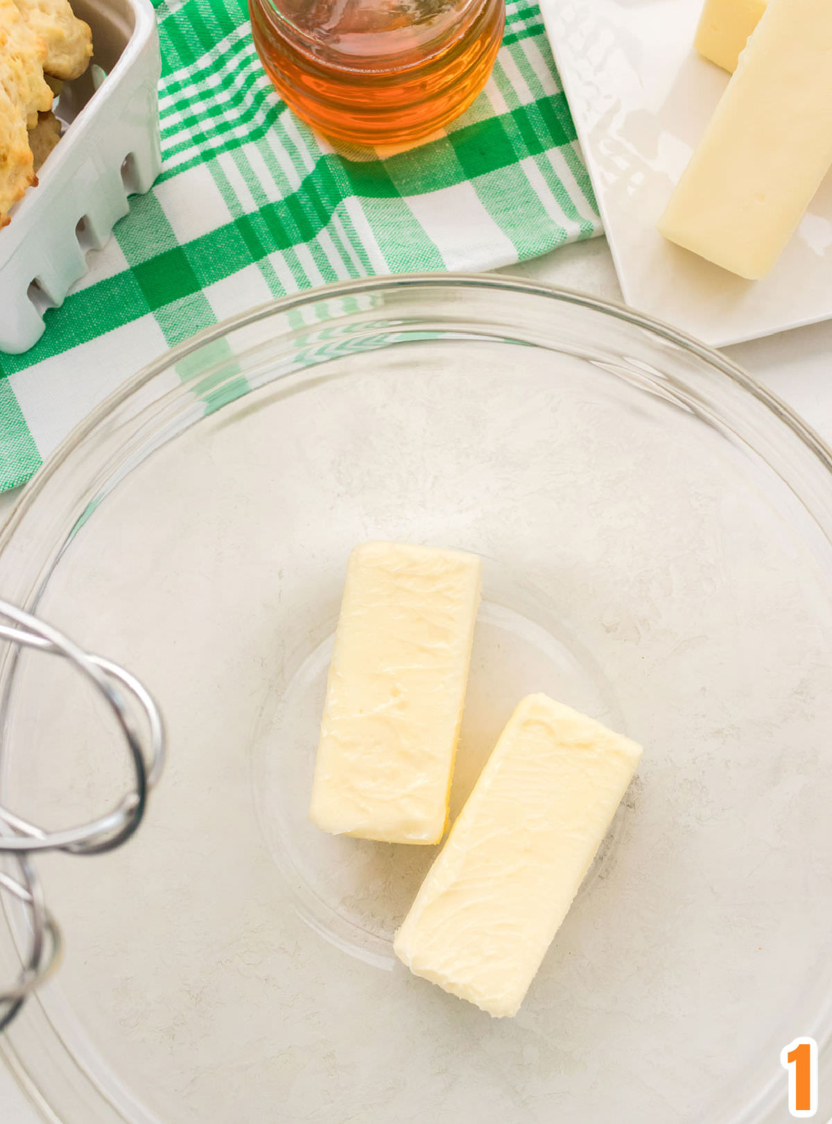 Overhead shot of a clear glass bowl with two sticks of butter in it.