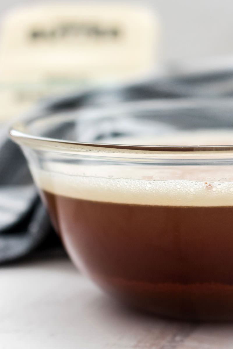 picture of brown butter in a clear bowl with a stick of butter in the background