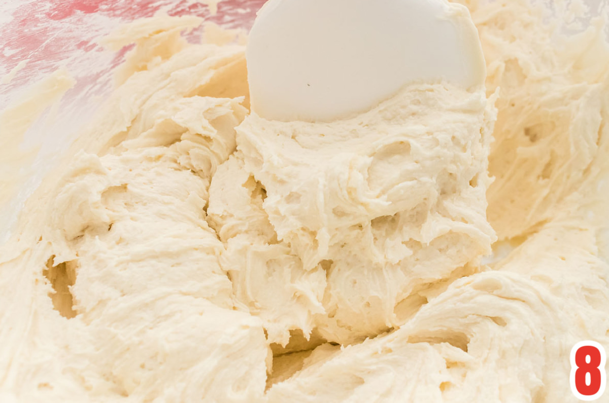 Closeup on a glass mixing bowl filled with Kahlua Frosting and a white spatula.