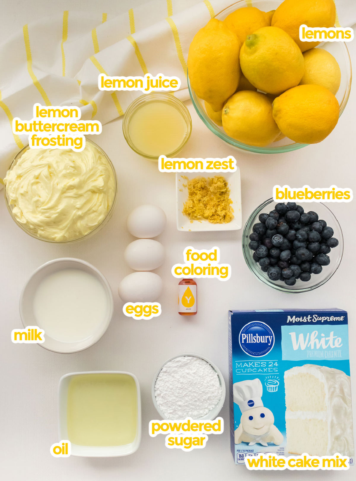 All the ingredients you will need to make Lemon Blueberry Cupcakes including lemons, lemon juice, lemon zest, lemon buttercream frosting, blueberries, milk, oil, eggs, powdered sugar, food coloring and white cake mix.