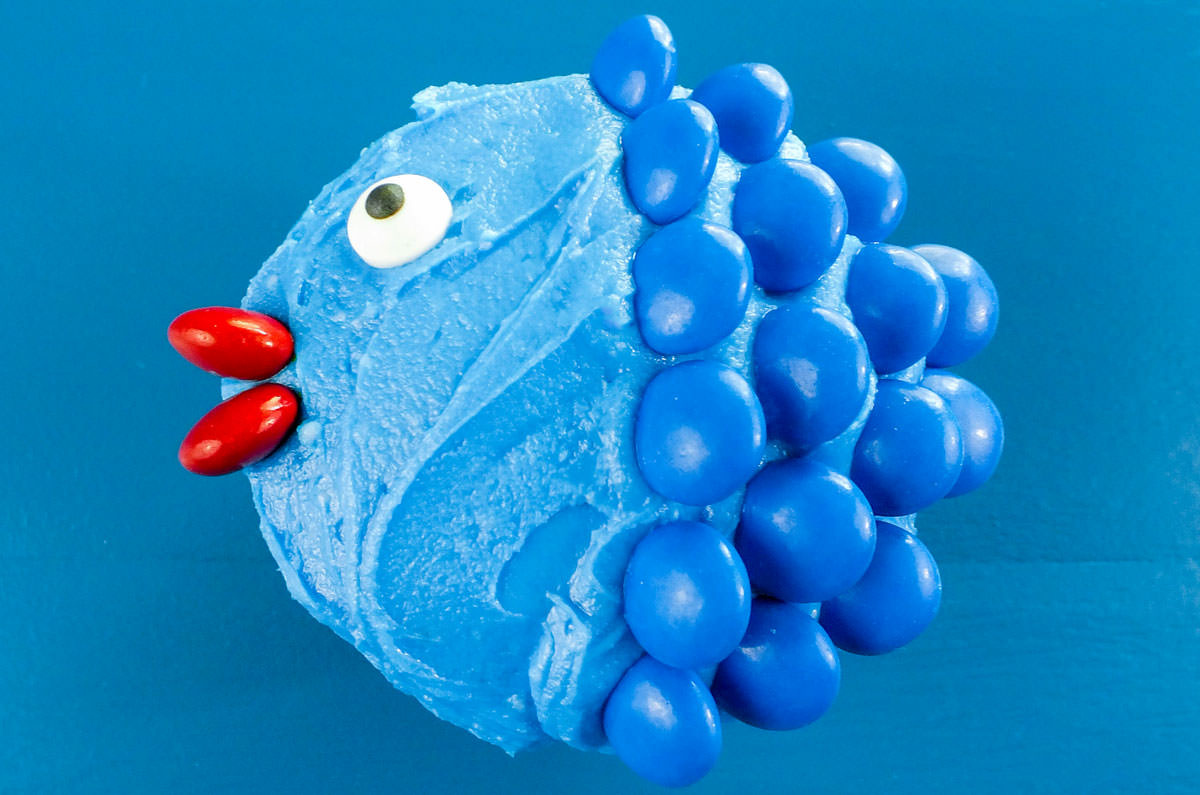 Closeup on a blue Little Fishy Cupcake sitting on a blue surface.