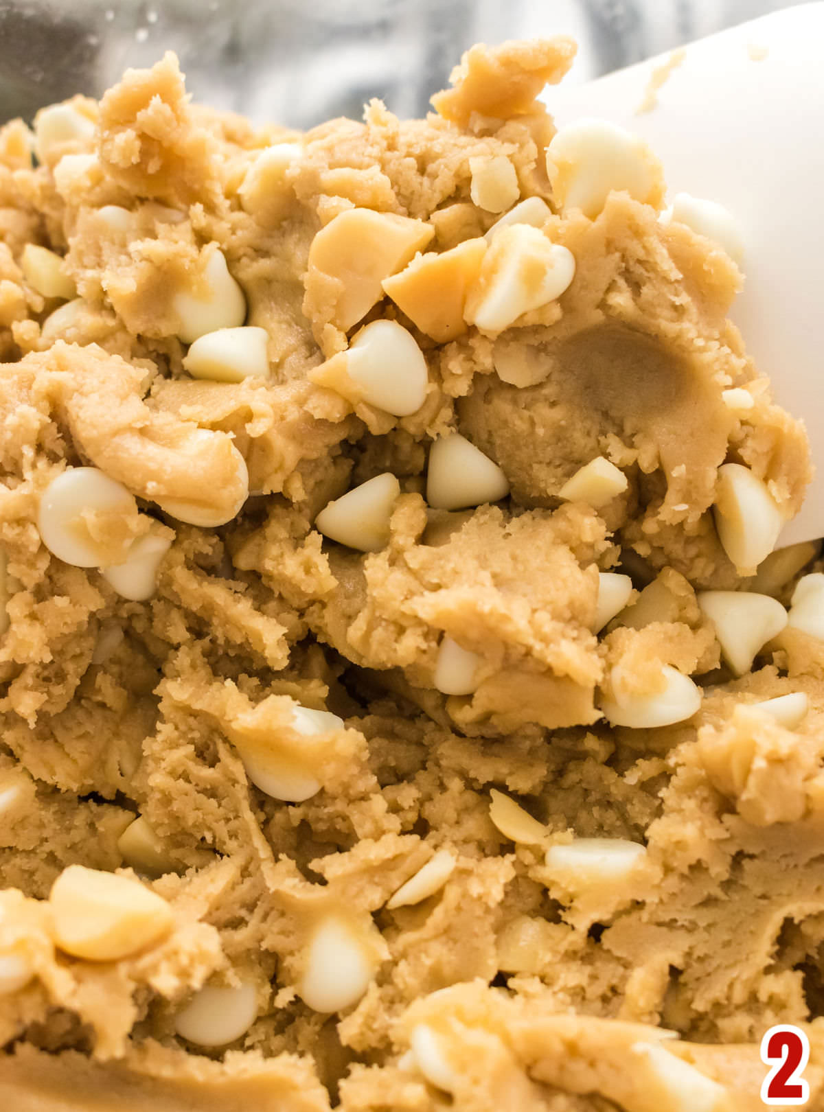 Closeup on a cookie dough in a white mixing bowl.