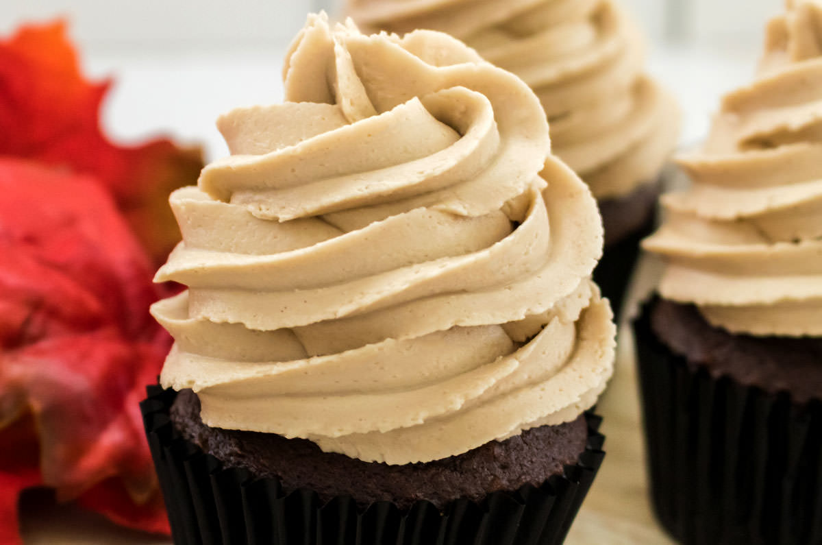 Closeup on three chocolate cupcakes topped with The Best Maple Buttercream Frosting.