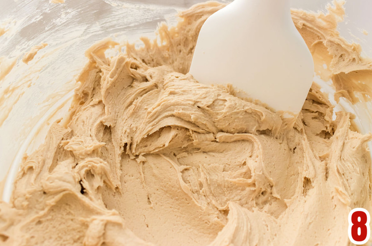 Closeup on a glass bowl filled with Maple Buttercream Frosting and a white spatula.