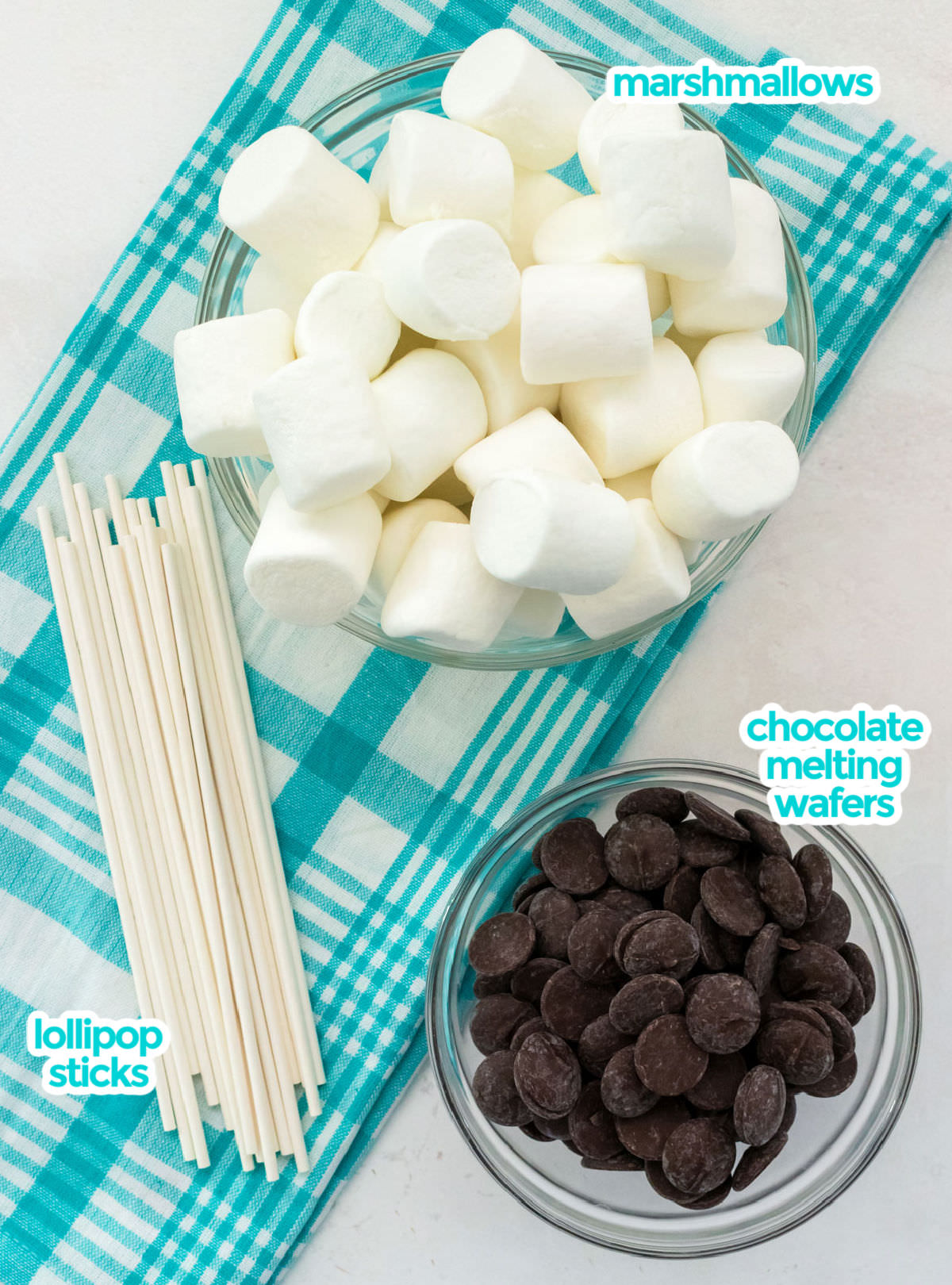 All the ingredients necessary to make Marshmallow Pops including marshmallows, chocolate melting wafers and lollipop sticks.