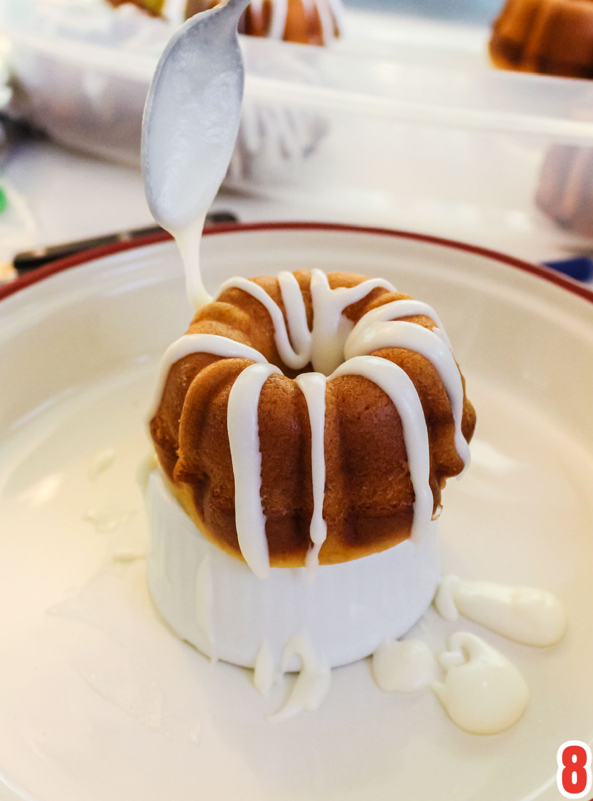 Closeup on a Mini Bundt Cake being drizzled with icing with a spoon.