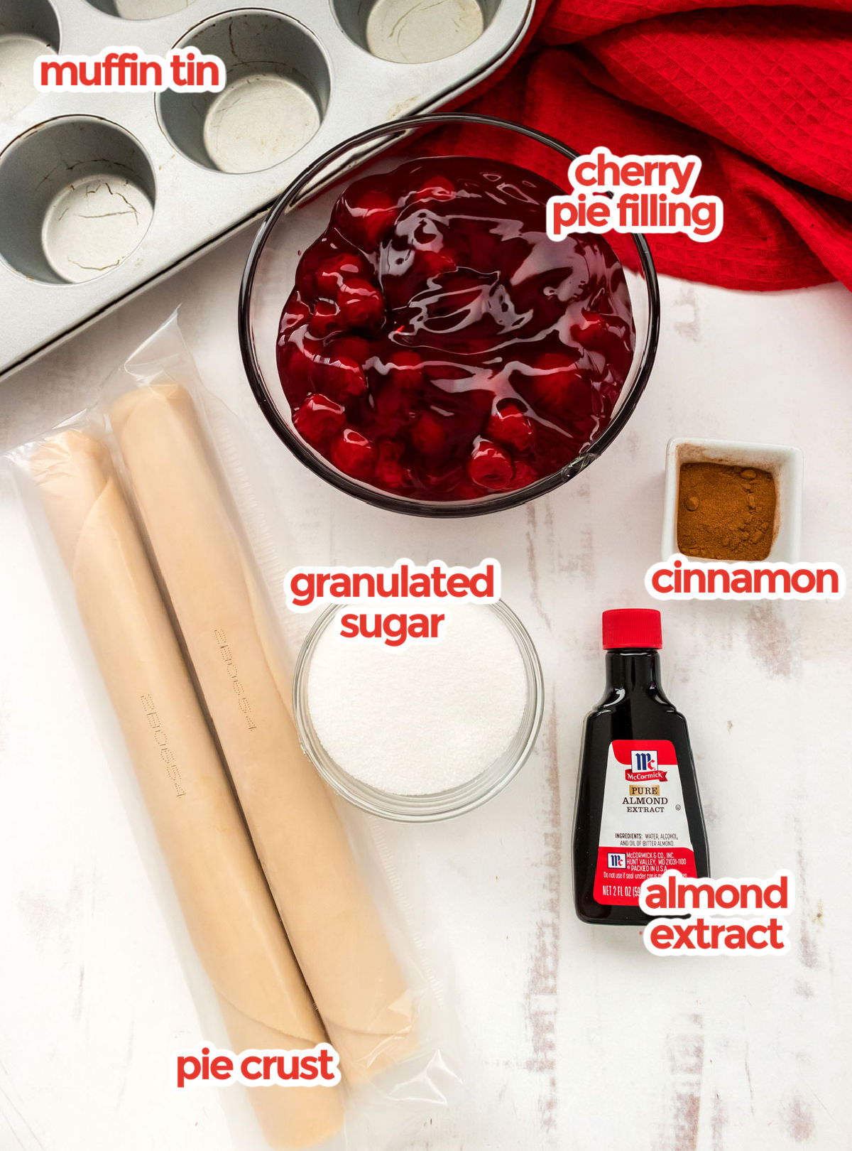 All the ingredients you will need to make Mini Cherry Pies including canned Cherry Pie Filling, Cinnamon, Almond Extract, Granulated Sugar and pre-made Pie Crust.