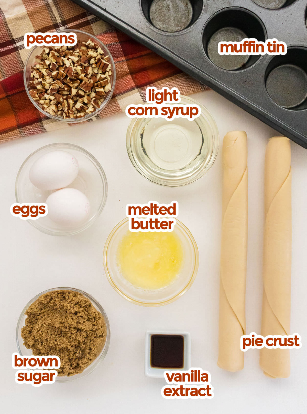 All the ingredients you will need to make Mini Pecan Pies including chopped pecans, light corn syrup, melted butter, eggs. vanilla extract, brown sugar and pie crusts.