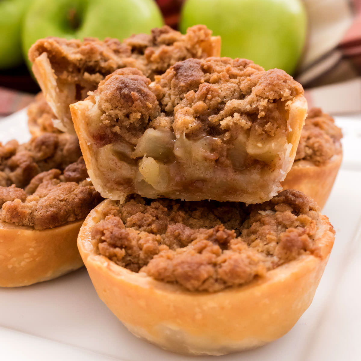 Closeup on a Mini Apple Pie that has been cut in half to show the filling and the crumb topping.