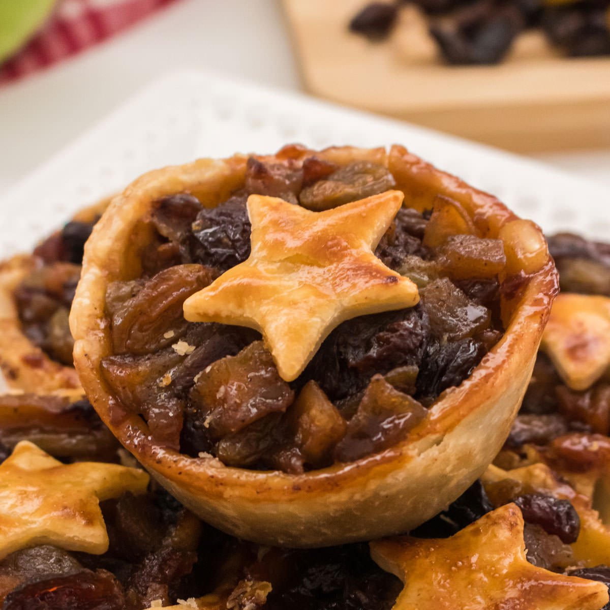 Closeup on a Mini Mince Pie sitting on a stack of other pies on a white plate.