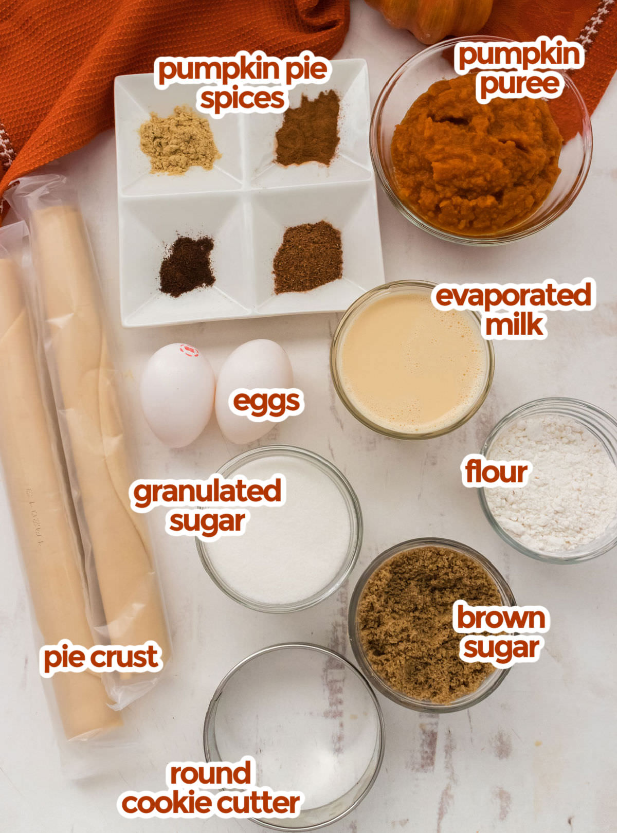 All the ingredients you will need to make Mini Pumpkin Pies including pie crust, pumpkin puree, pumpkin pie spices, evaporated milk, eggs, sugars and flour. 