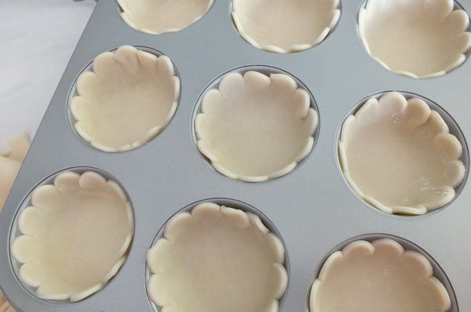 Press pie dough into the muffin tins