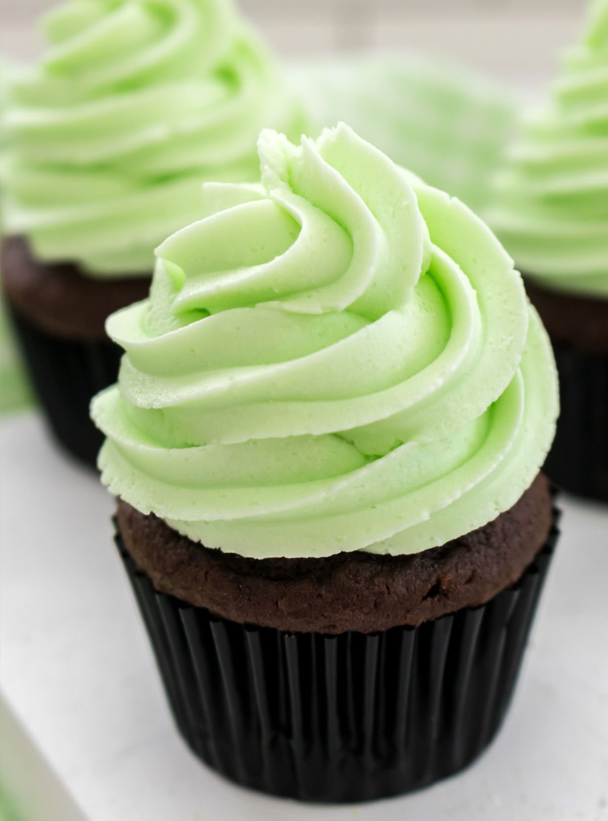 Closeup of a chocolate cupcake frosted with The Best Mint Buttercream Frosting.