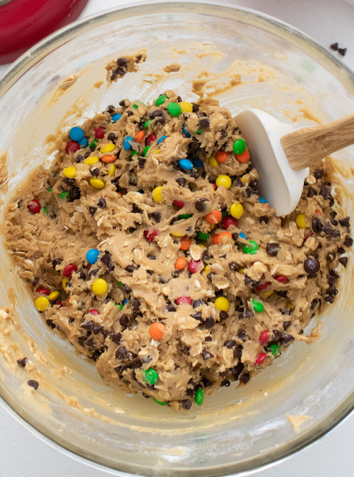 Glass mixing bowl filled with the cookie dough for a batch of Monster Cookies.