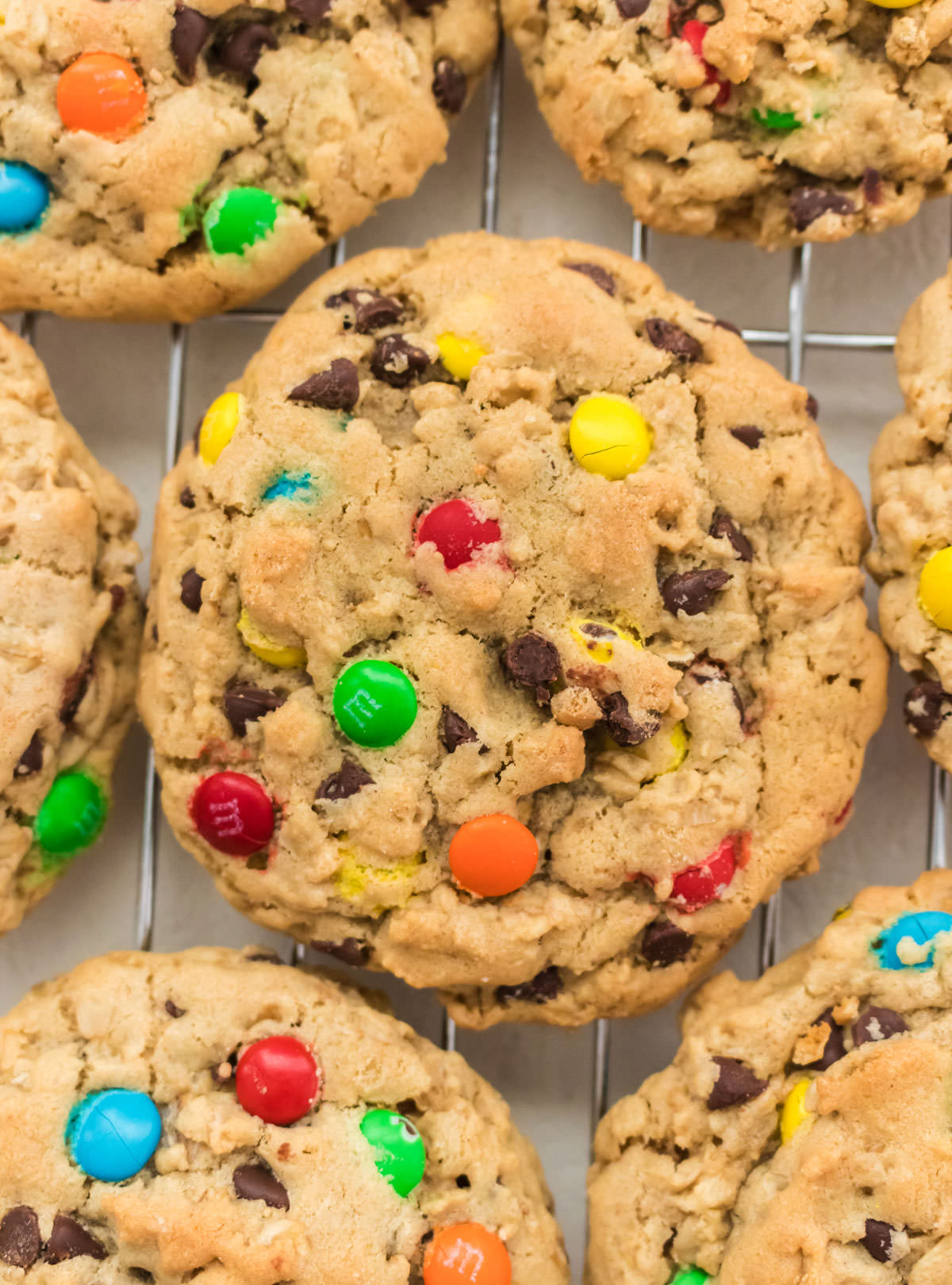 Close up of a Monster Cookie sitting on a wire cooling rack.