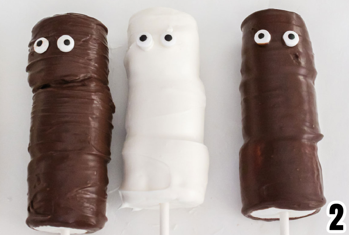 Closeup on three chocolate covered Mummy Marshmallow Pops.