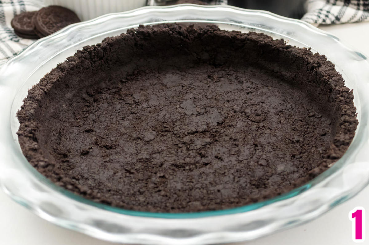 Closeup on a clear pie plate filled with a Oreo Cookie Crust.