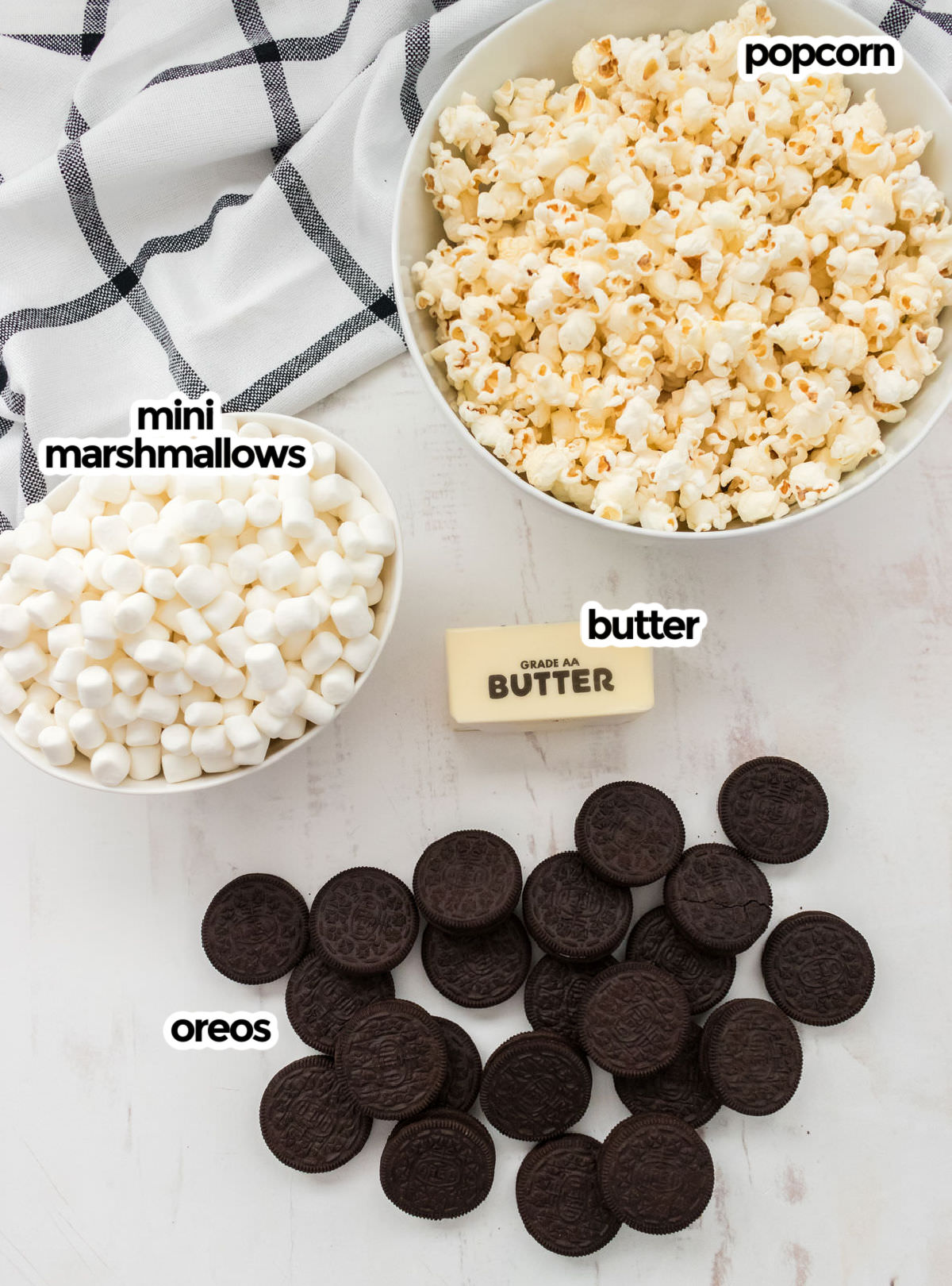 All the ingredients you will need to make Oreo Popcorn including popcorn, mini marshmallows, butter and Oreo Cookies.