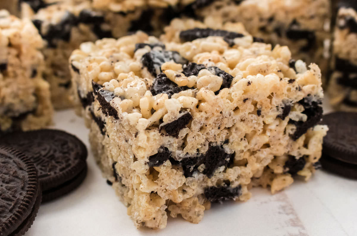 Closeup on a stack of Oreo Rice Krispie Treats sitting on a white surface next to a stack of Oreo Cookies.
