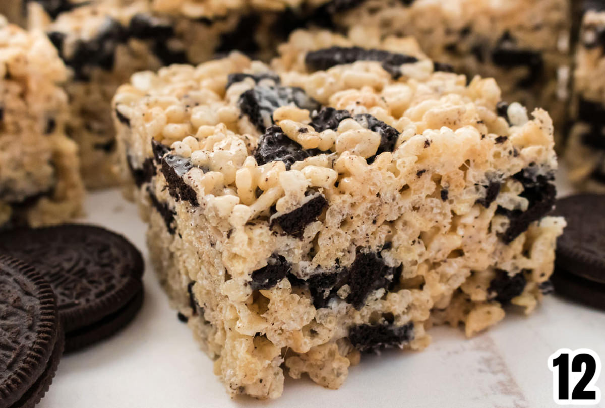 Closeup on an Oreo Rice Krispie Treat sitting in front of more cookie bars an a stack of Oreo Cookies.