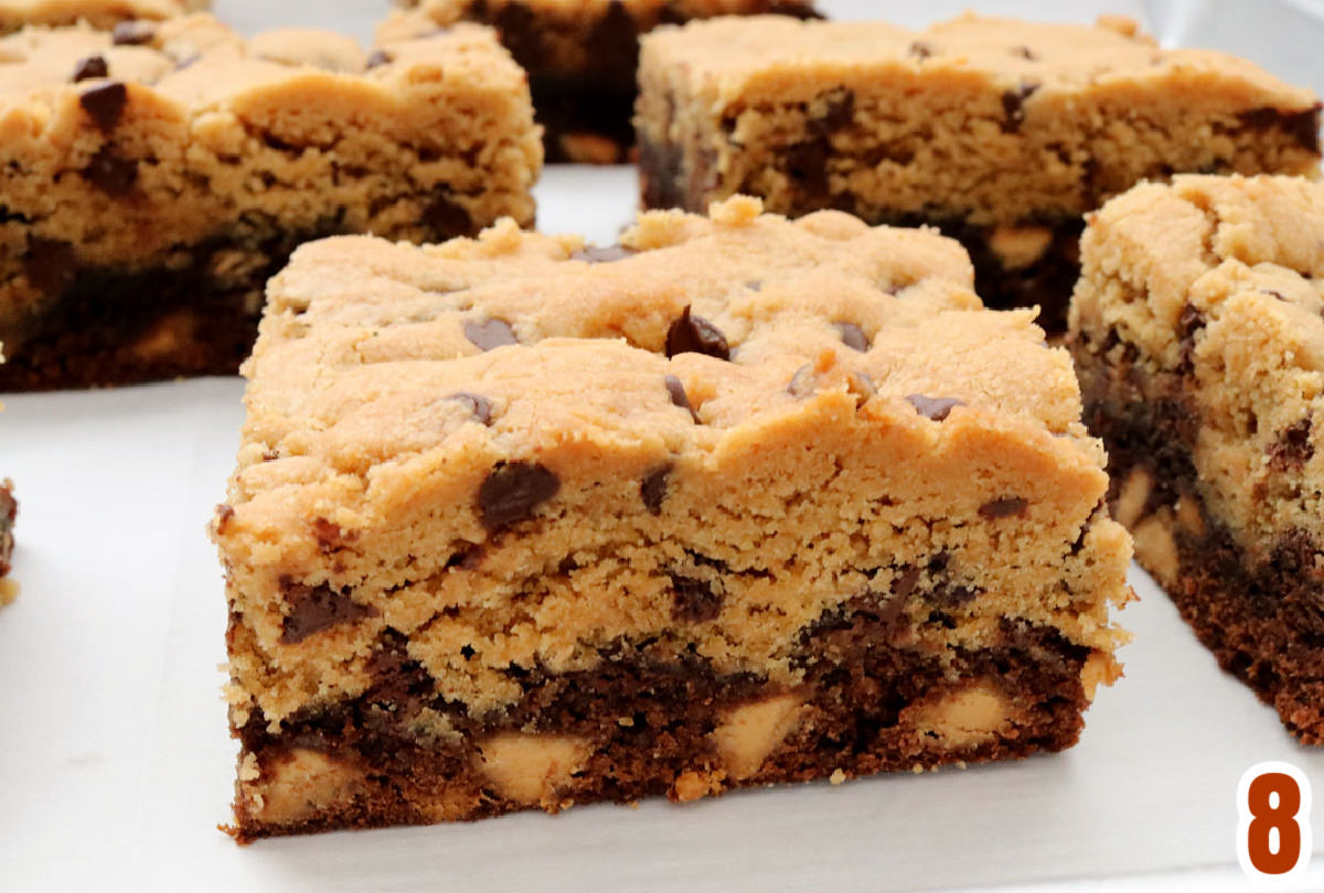 Closeup on individual bars of Peanut Butter Brookies sitting in rows on a piece of parchment paper.