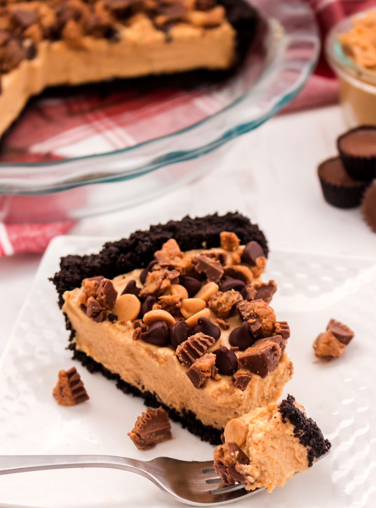 Closeup on a single piece of Peanut Butter Pie on a white plate with a fork with a piece of the pie on it.