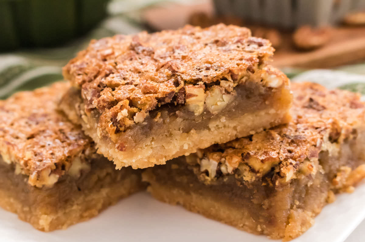 Closeup on a stack of three Pecan Pie  Bars sitting on a white plate.