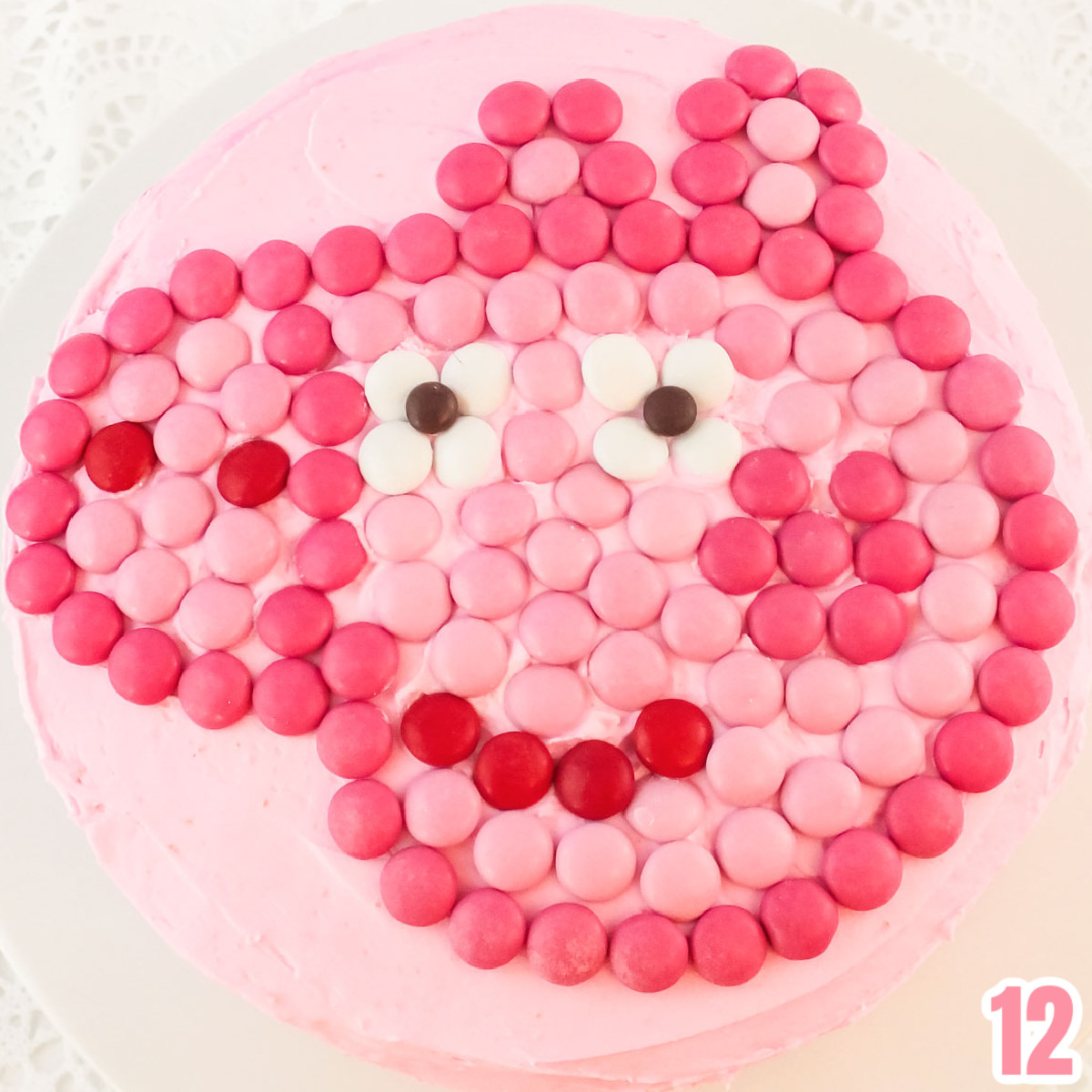 Closeup on the top of a Peppa Pig Cake showing the Peppa face made out of Pink M&M's.