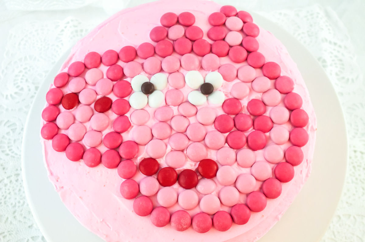 Closeup on a top view of an Easy Peppa Pig Birthday Party Cake sitting on a white cake plate on a white table.