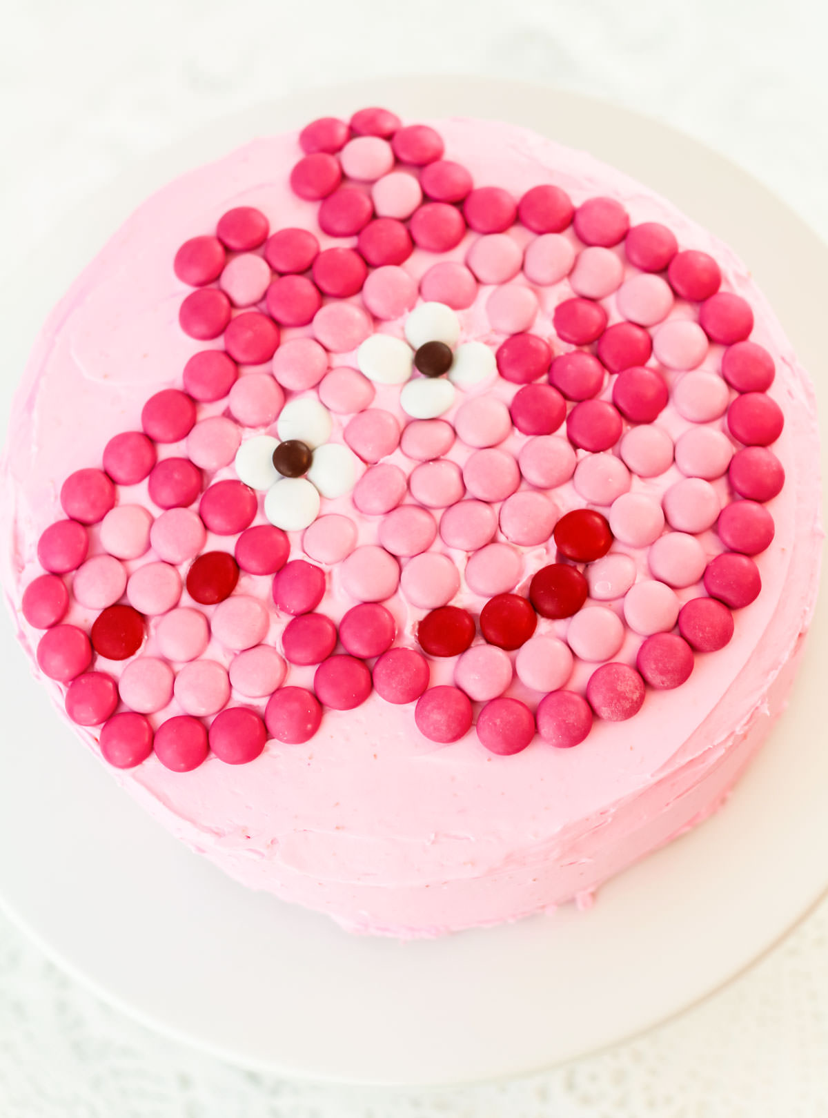 Closeup of an Easy Peppa Pig Cake sitting on a white cake plate on a white table.