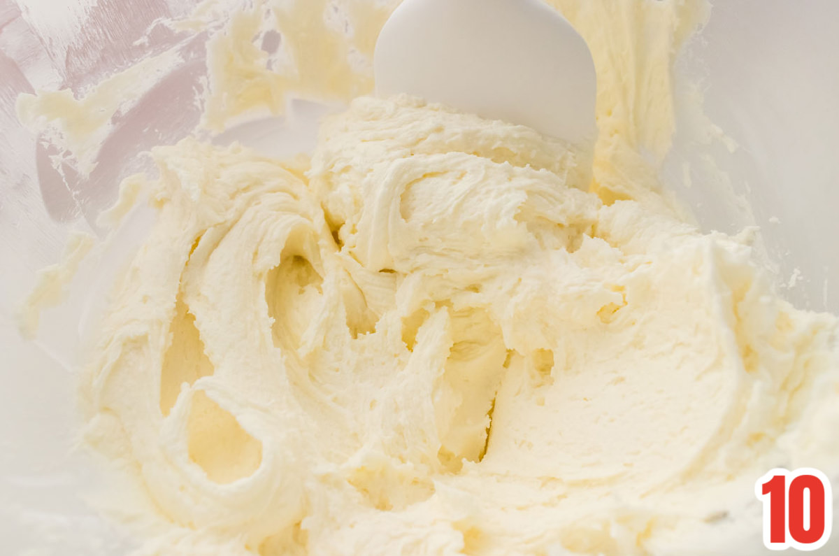 Closeup on a clear glass mixing bowl filled with homemade Peppermint Buttercream Frosting.