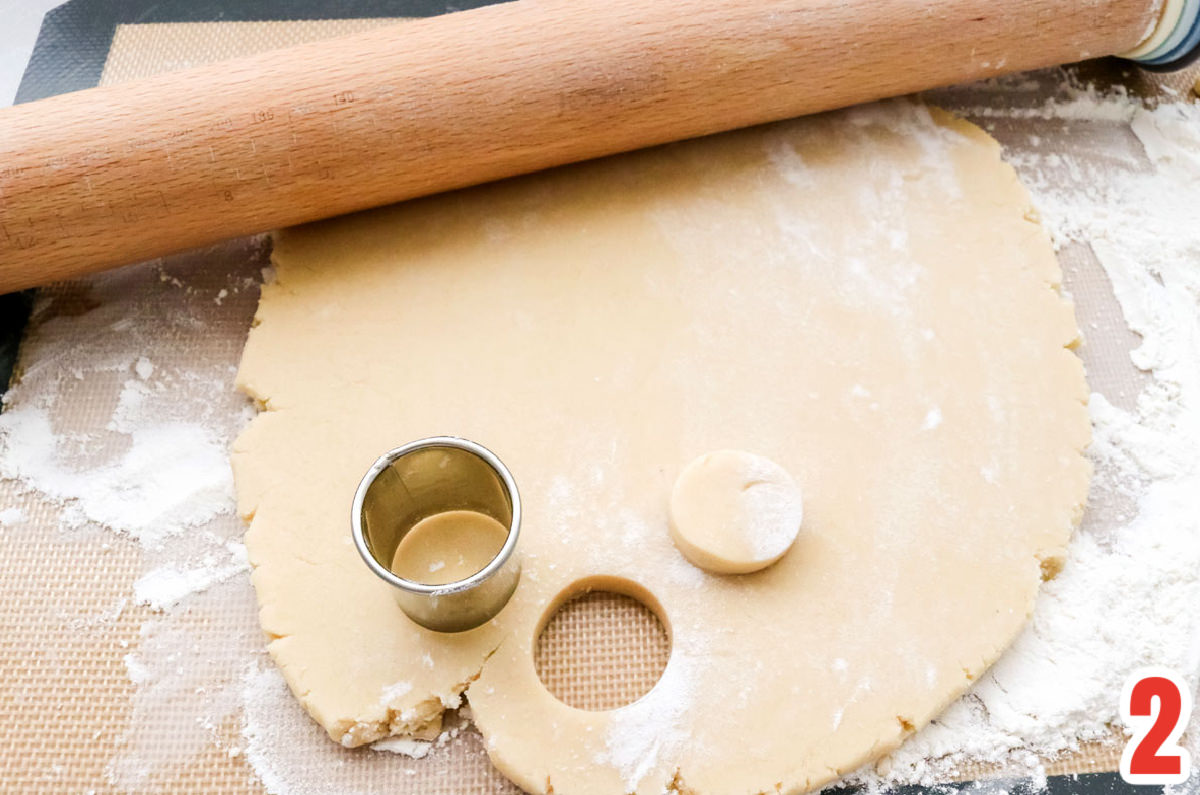 Sugar cooke dough rolled out with a circle cookie cutter and a rolling pin.