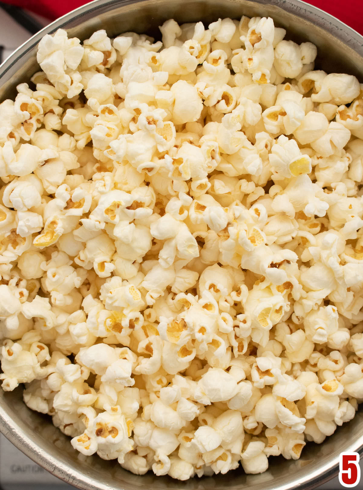Closeup on a large pan filled with homemade popcorn made on a stovetop.