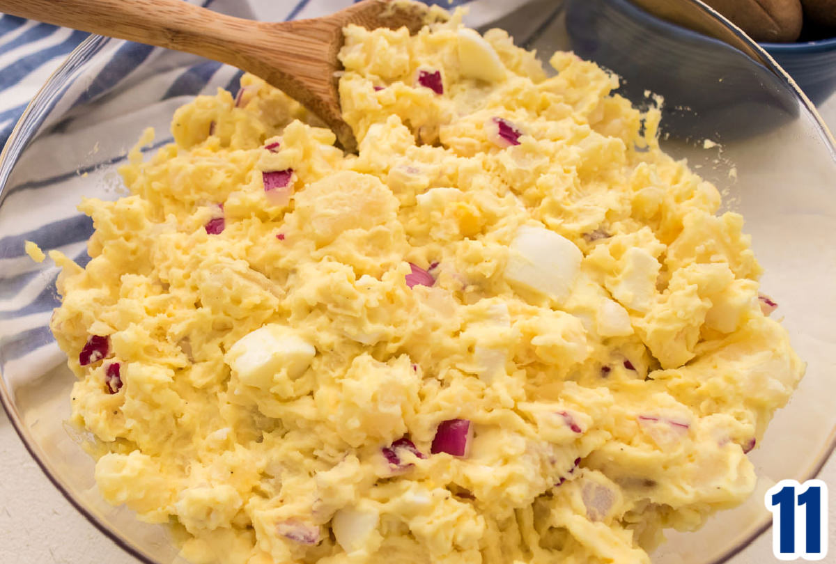Closeup on a clear bowl filled with Potato Salad that as been sprinkled with Paprika.