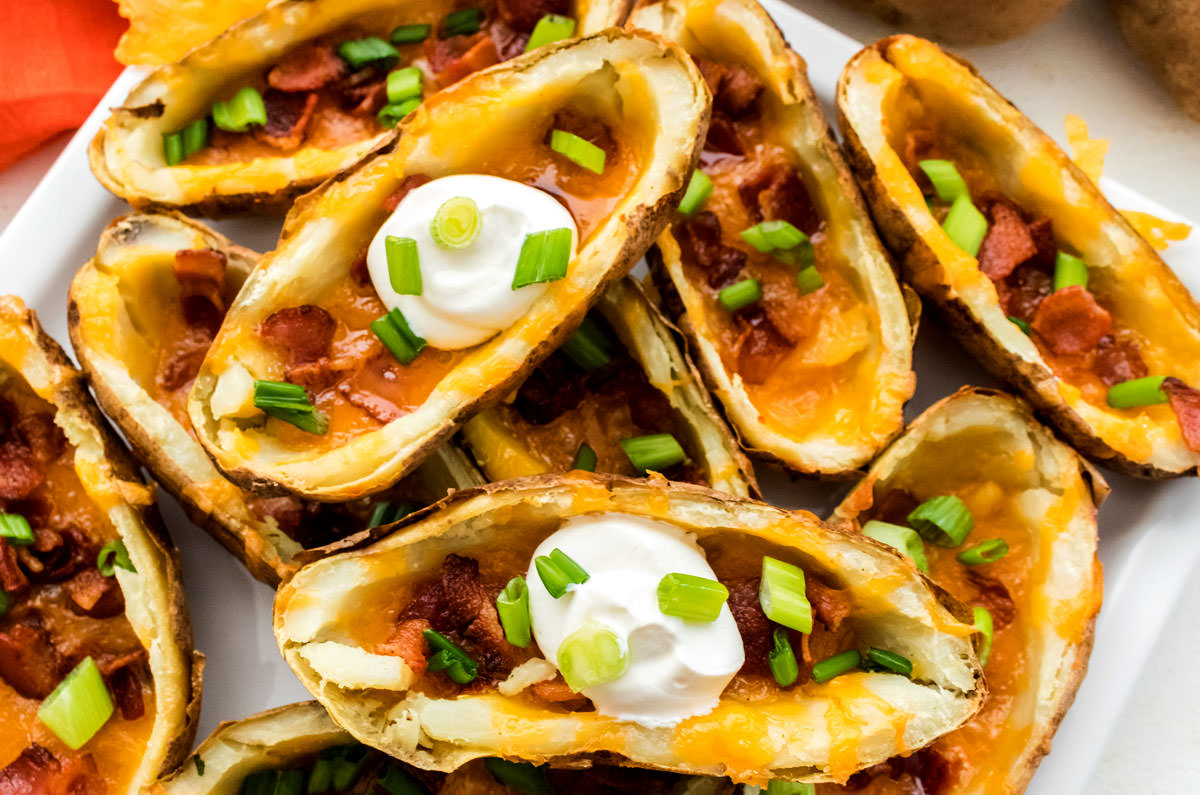 Closeup on a stack of Potato Skins sitting on a white serving platter.