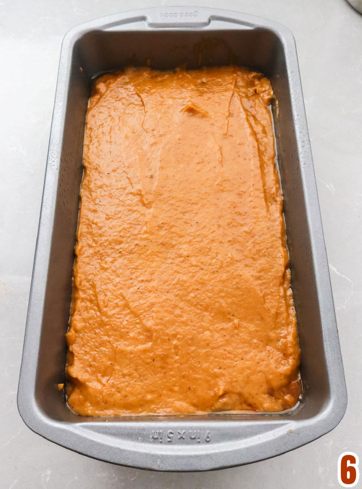 Closeup on a 9x5" loaf pan filled with Pumpkin Bread batter.
