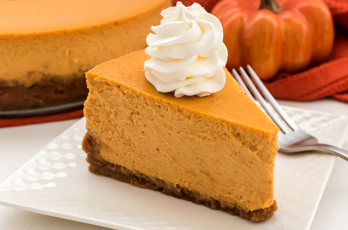 Closeup on a single piece of Pumpkin Cheesecake topped with Whipped Cream.