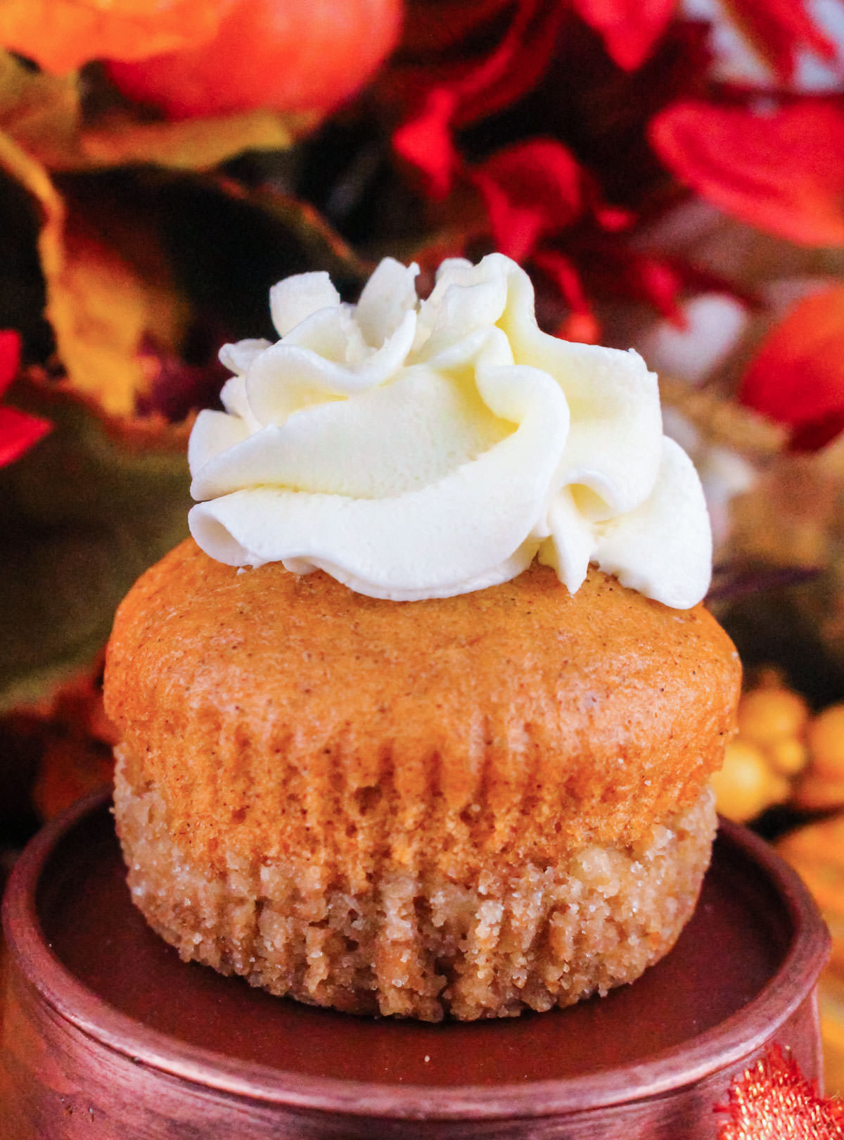 Closeup on a Pumpkin Pie Cupcake sitting on a pedestal in front of Fall party decorations.