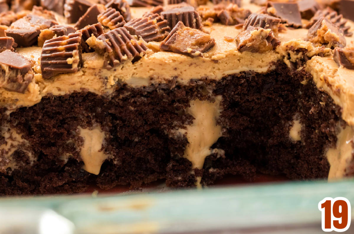 Closeup of the inside of the Peanut Butter Poke Cake topped with Reese's Peanut Butter Cups.