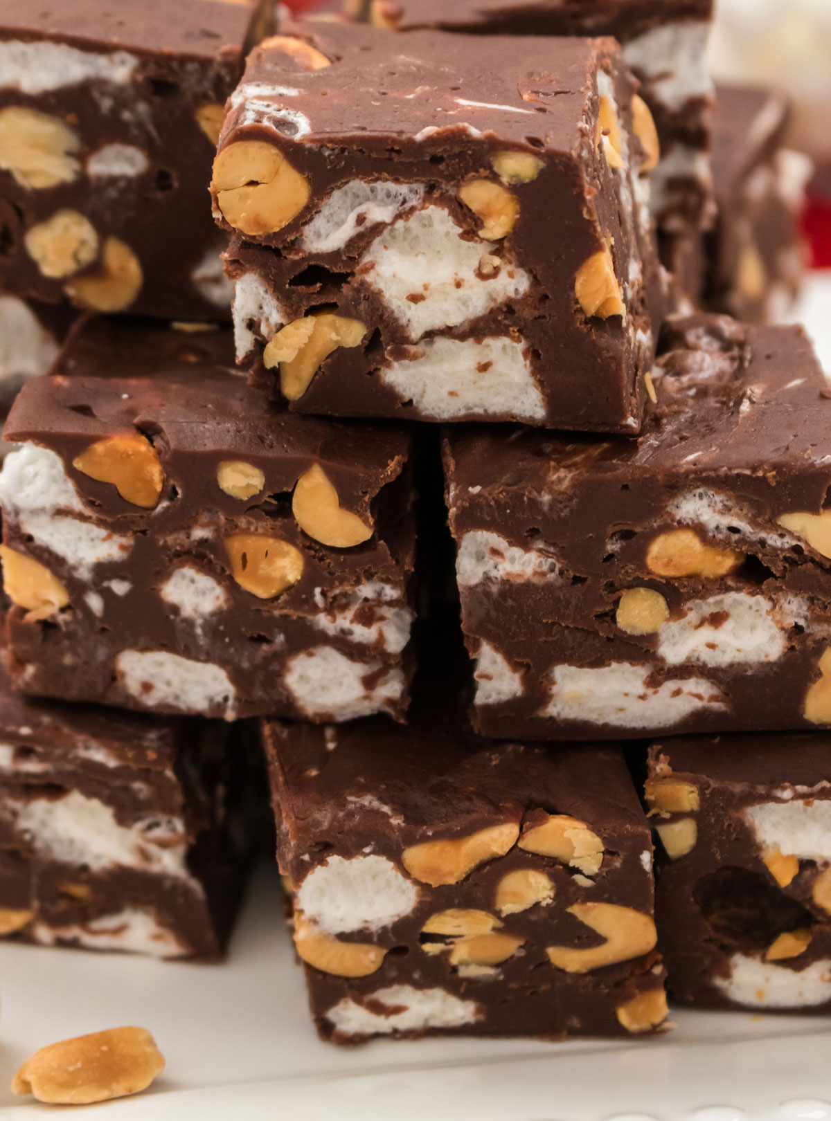 Closeup on a stack of Rocky Road Fudge candy pieces sitting in a stack on a white serving platter.