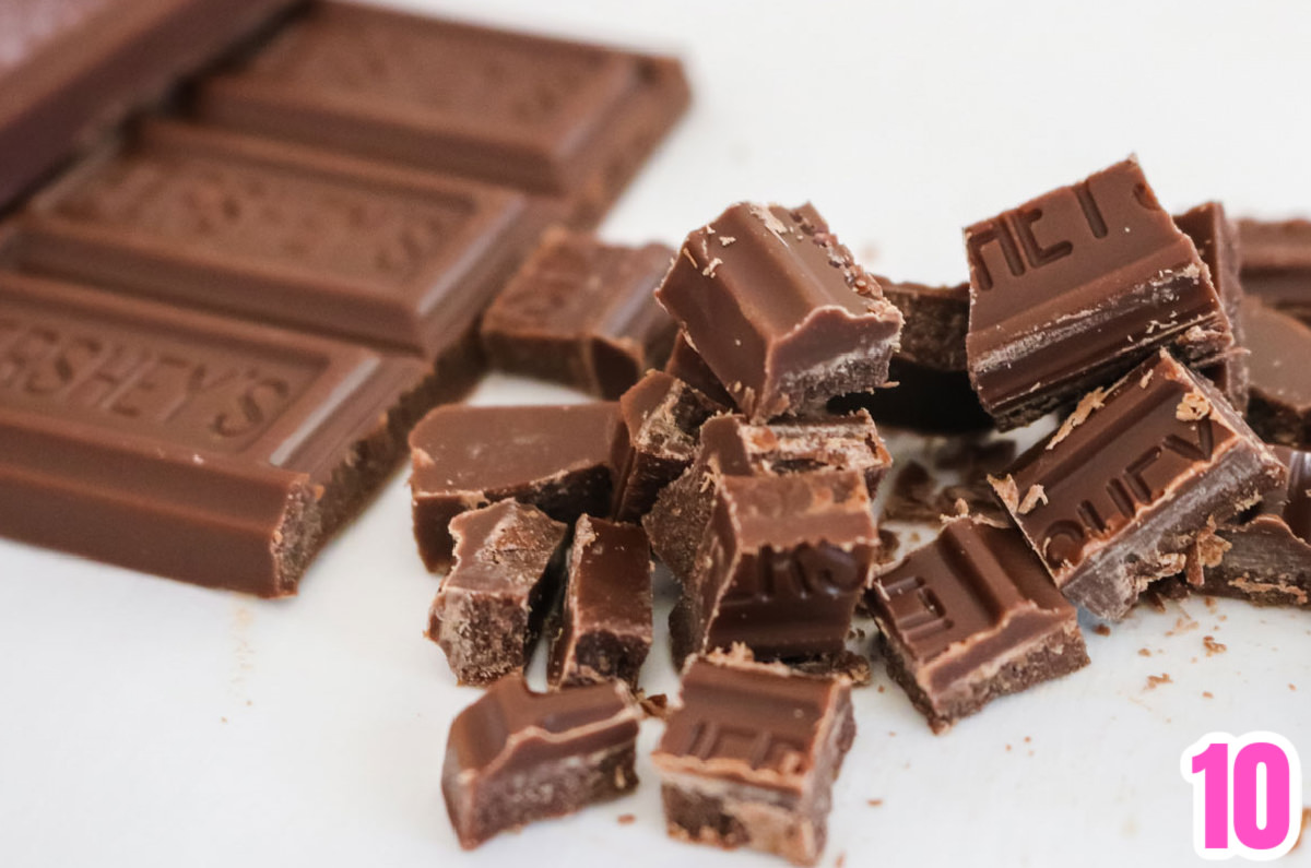 Closeup on a Hershey Chocolate Bar partly chopped into pieces, sitting on a white table.